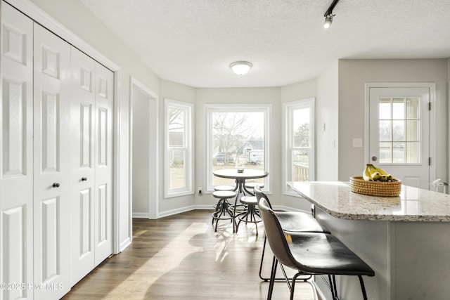 dining space with a textured ceiling, baseboards, and wood finished floors