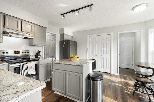 kitchen with dark wood-type flooring, under cabinet range hood, gray cabinets, stainless steel appliances, and a textured ceiling