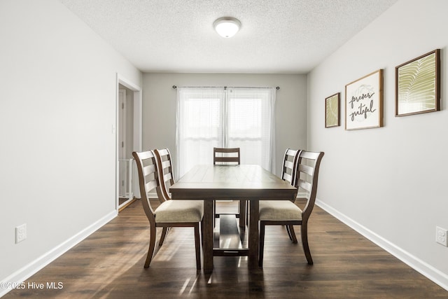 dining area featuring dark wood finished floors, a textured ceiling, and baseboards