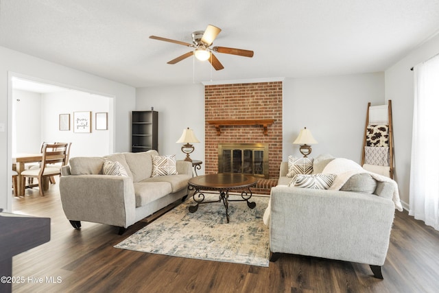 living area with a fireplace, dark wood-style floors, and a ceiling fan