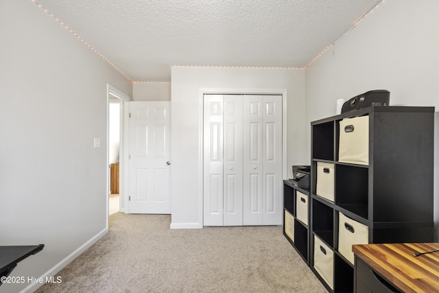 interior space featuring a textured ceiling, baseboards, and carpet floors