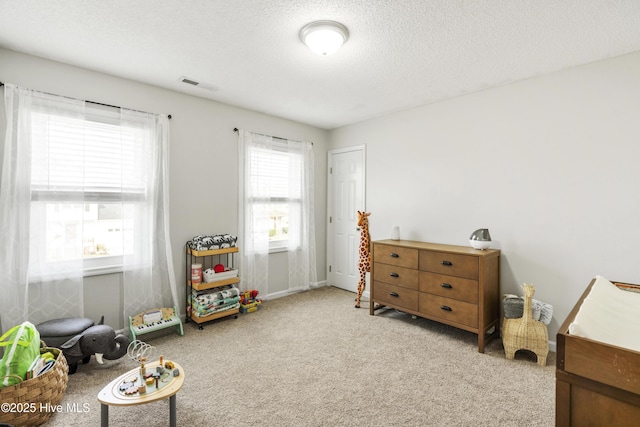 living area featuring visible vents, carpet floors, and a textured ceiling