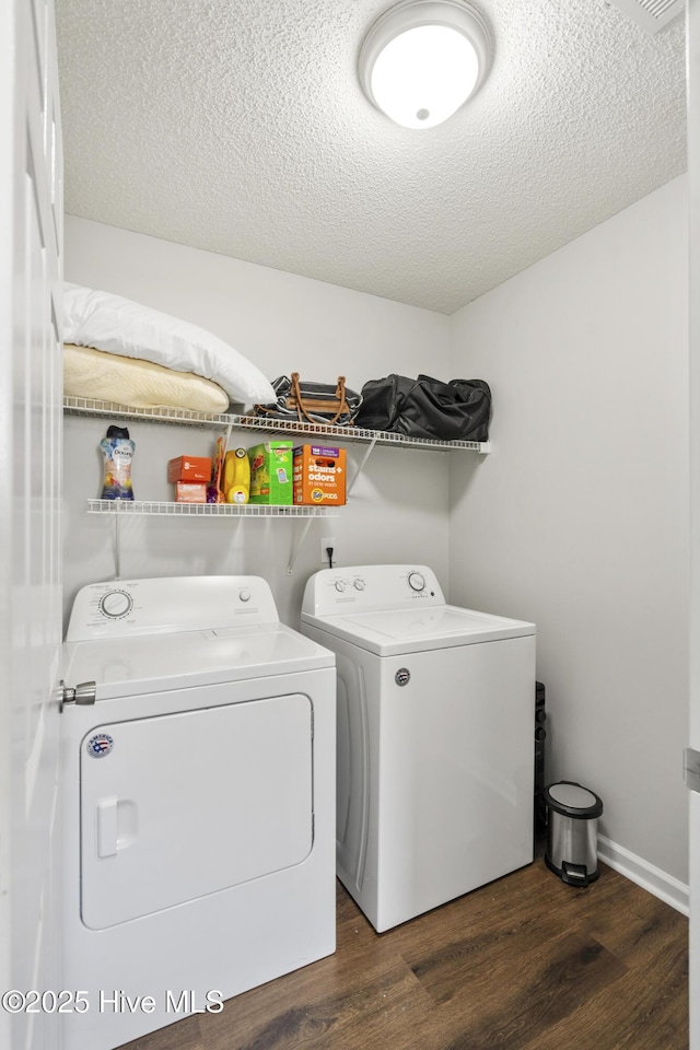 washroom with laundry area, washer and dryer, a textured ceiling, and wood finished floors