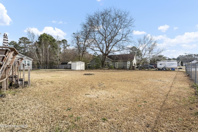 view of yard featuring an outdoor structure, a storage unit, and fence