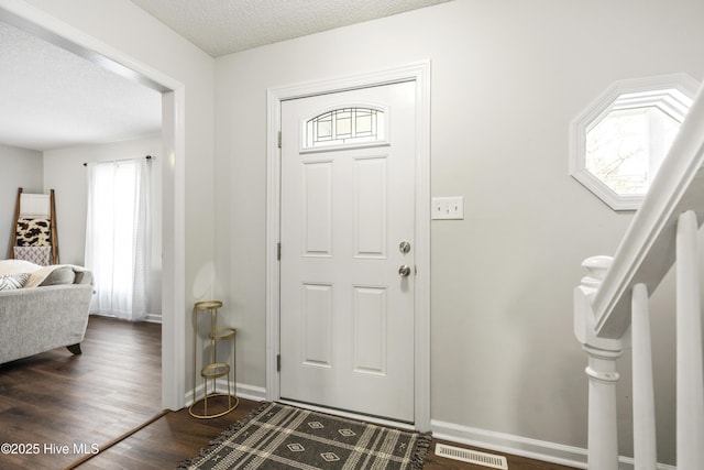 entryway featuring baseboards, visible vents, dark wood-style flooring, and a textured ceiling