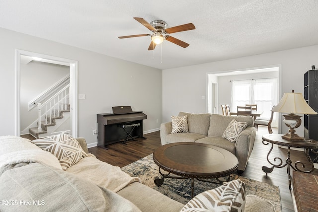 living room featuring baseboards, ceiling fan, stairway, wood finished floors, and a textured ceiling