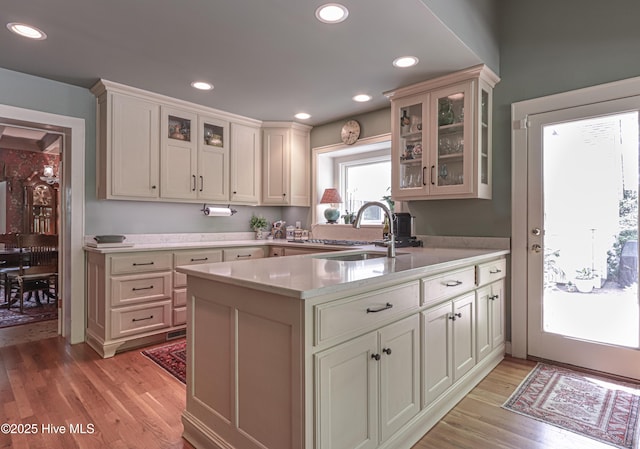 1335 Midland Rd, Southern Pines, NC 28387 - kitchen with a sink, light wood-style flooring, a peninsula, glass insert cabinets, and recessed lighting