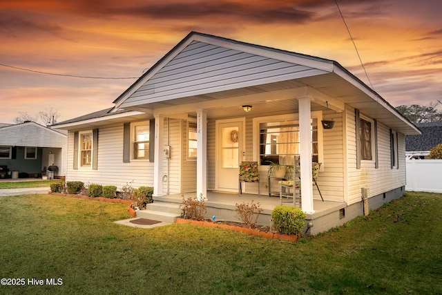 bungalow-style home with crawl space, a lawn, a porch, and fence