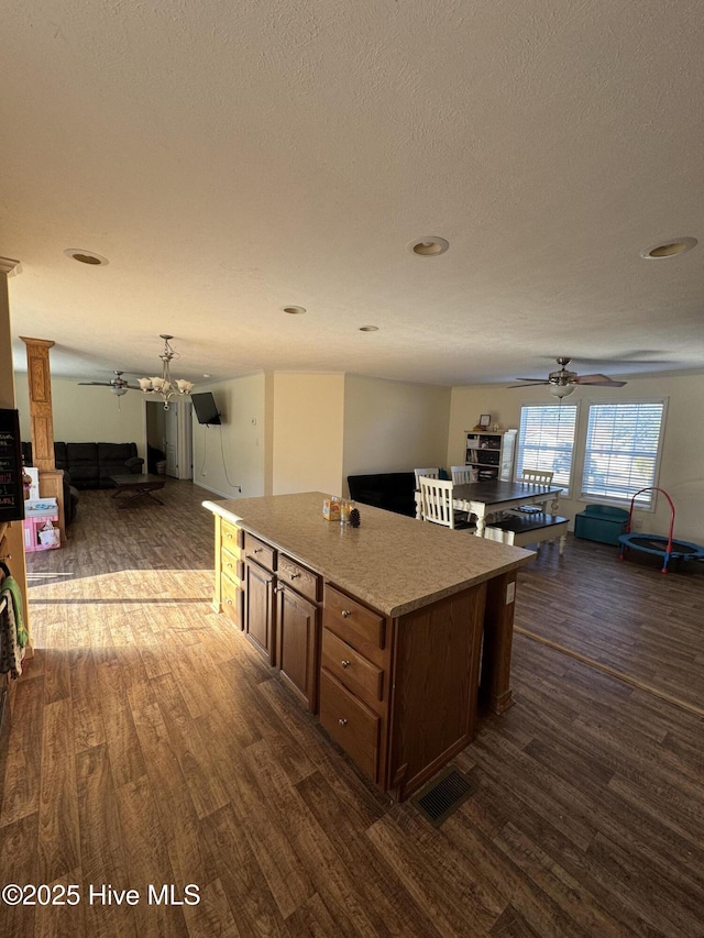 kitchen featuring ornate columns, open floor plan, a ceiling fan, and dark wood-style flooring