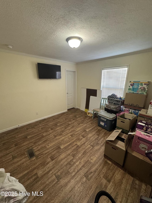 interior space with visible vents, crown molding, baseboards, wood finished floors, and a textured ceiling