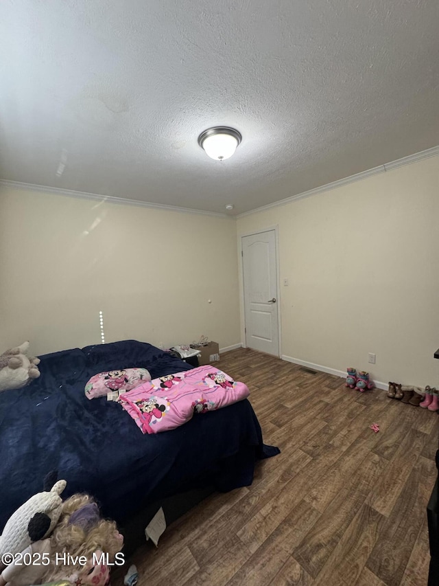 bedroom with a textured ceiling, wood finished floors, and crown molding
