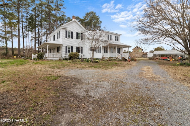 view of front facade with gravel driveway, a porch, and a chimney