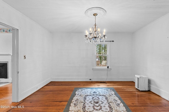 dining area with a fireplace, crown molding, a notable chandelier, and wood finished floors