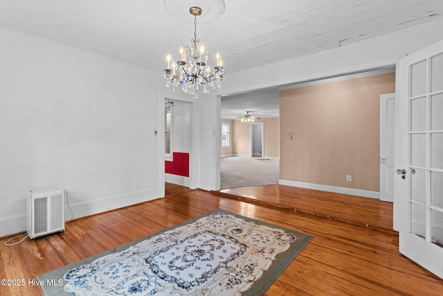 interior space featuring ceiling fan with notable chandelier, baseboards, and hardwood / wood-style floors