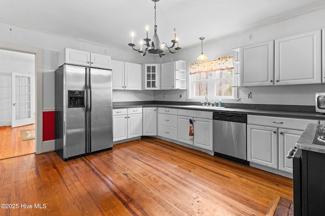 kitchen featuring a chandelier, appliances with stainless steel finishes, dark countertops, and a sink