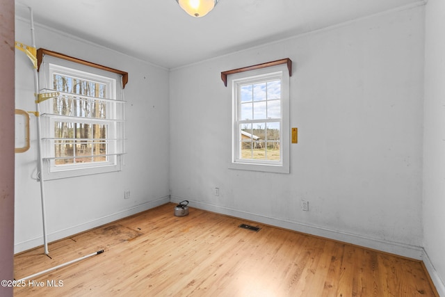 spare room featuring visible vents, baseboards, and wood finished floors