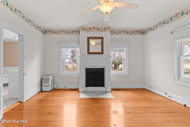 unfurnished living room with visible vents, a fireplace with flush hearth, ceiling fan, and wood finished floors