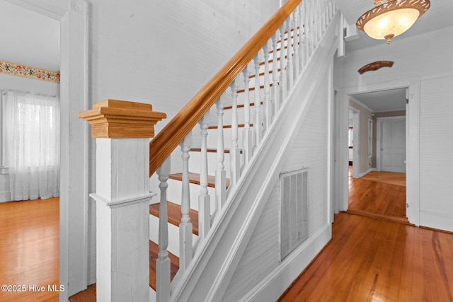 stairway featuring wood finished floors and visible vents