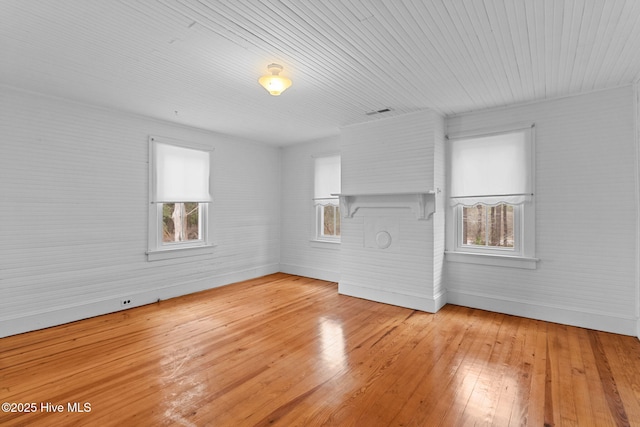 empty room featuring brick wall, baseboards, and light wood-style floors