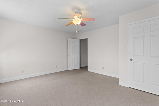 carpeted spare room with baseboards, a textured ceiling, and ceiling fan