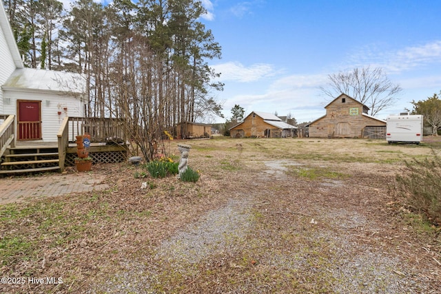 view of yard with an outbuilding, a barn, driveway, and a deck