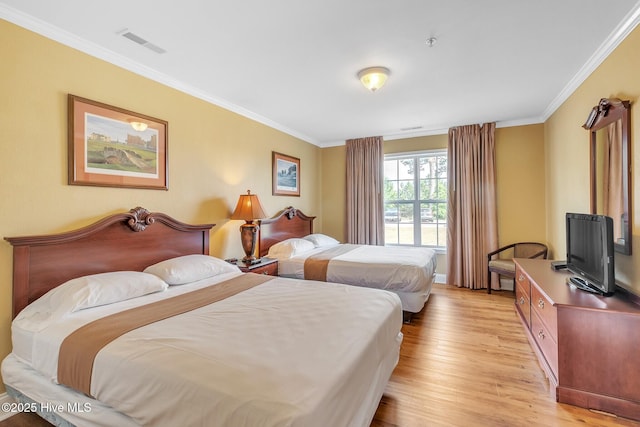 bedroom featuring visible vents, ornamental molding, and light wood finished floors