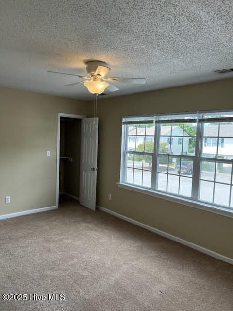 empty room with visible vents, baseboards, carpet floors, and ceiling fan