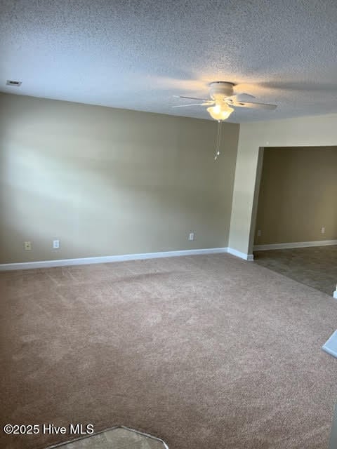 spare room featuring baseboards, a textured ceiling, a ceiling fan, and carpet floors