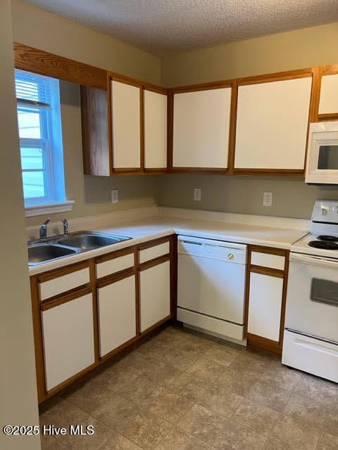 kitchen with white appliances, white cabinets, light countertops, and a sink