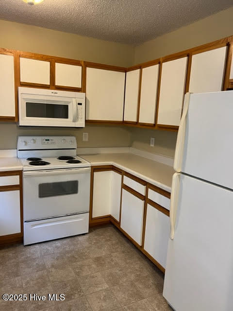 kitchen featuring white cabinetry, white appliances, light countertops, and a textured ceiling