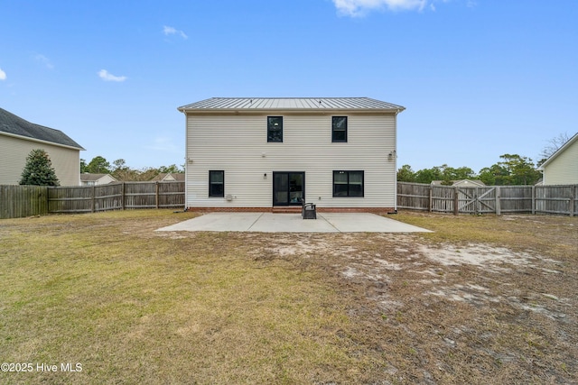 rear view of property with a lawn, a standing seam roof, a fenced backyard, metal roof, and a patio area