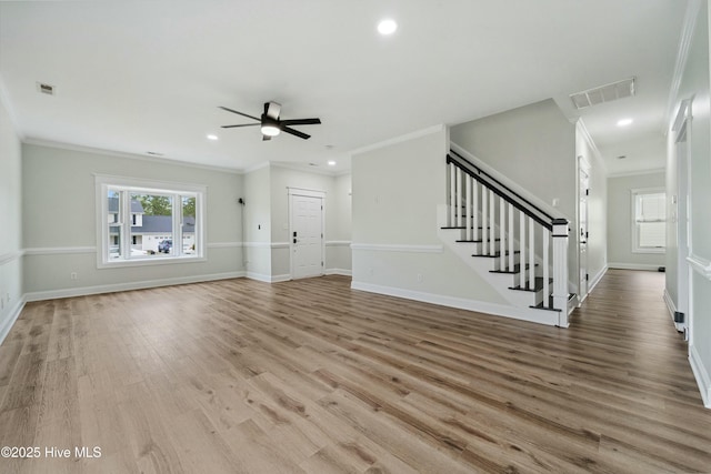 unfurnished living room featuring visible vents, ornamental molding, a ceiling fan, wood finished floors, and stairway