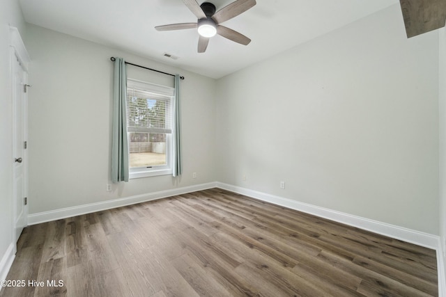 unfurnished room with a ceiling fan, wood finished floors, visible vents, and baseboards