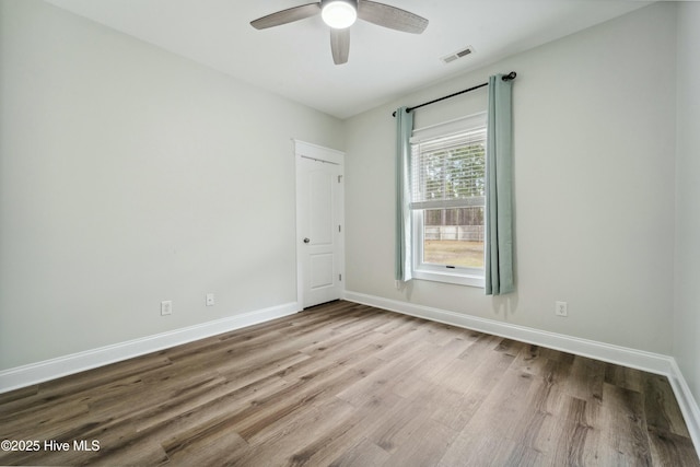 unfurnished room featuring visible vents, a ceiling fan, baseboards, and wood finished floors