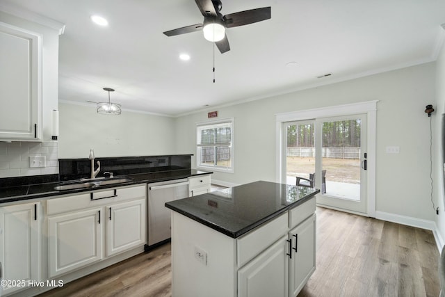 kitchen featuring light wood-style flooring, a sink, stainless steel dishwasher, crown molding, and decorative backsplash