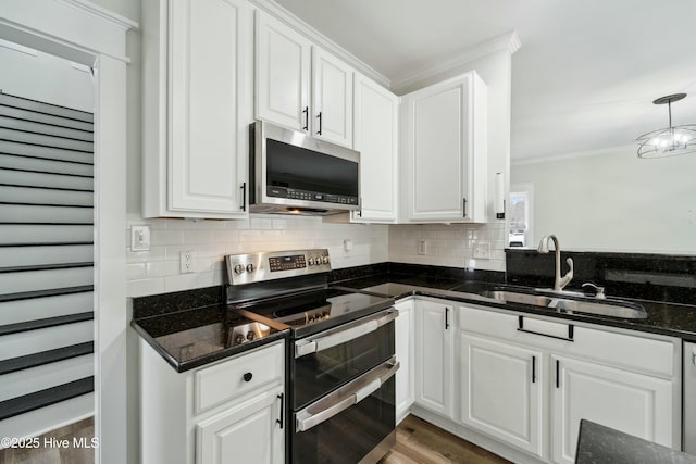 kitchen featuring ornamental molding, decorative backsplash, white cabinets, stainless steel appliances, and a sink