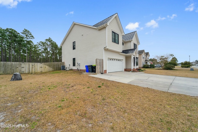 view of home's exterior with fence, metal roof, a yard, driveway, and a standing seam roof