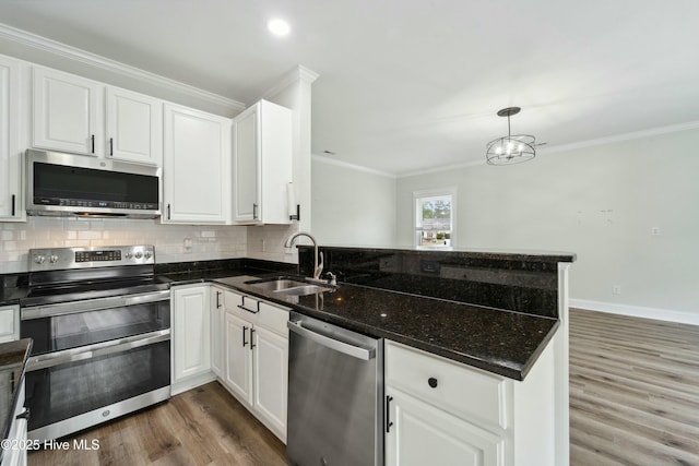 kitchen with a sink, a peninsula, crown molding, and stainless steel appliances