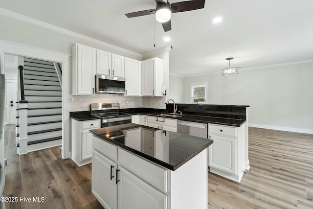 kitchen featuring a ceiling fan, a peninsula, a sink, stainless steel appliances, and backsplash