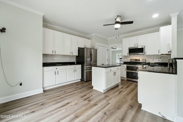 kitchen with a sink, a kitchen island, dark countertops, stainless steel appliances, and ceiling fan