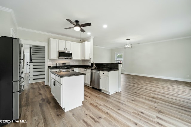 kitchen featuring a peninsula, ceiling fan, decorative backsplash, appliances with stainless steel finishes, and dark countertops