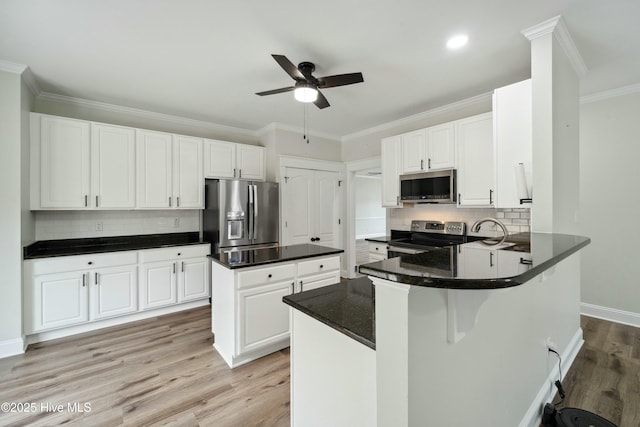 kitchen featuring light wood-type flooring, stainless steel appliances, ornamental molding, and a ceiling fan