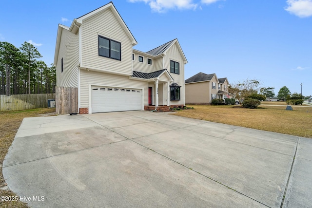 traditional home featuring fence, a standing seam roof, an attached garage, concrete driveway, and metal roof