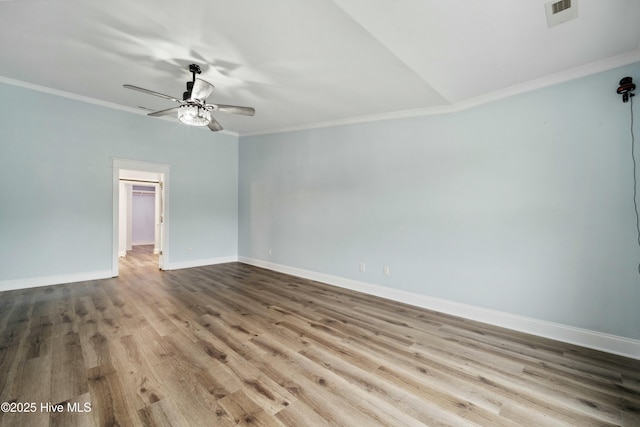 spare room featuring wood finished floors, a ceiling fan, visible vents, baseboards, and crown molding