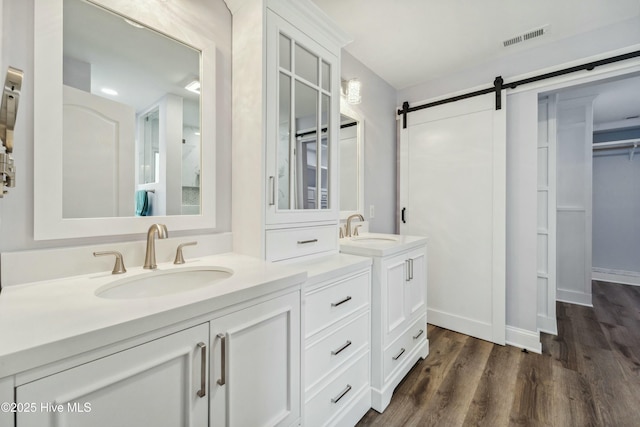 full bath with vanity, wood finished floors, visible vents, baseboards, and a spacious closet