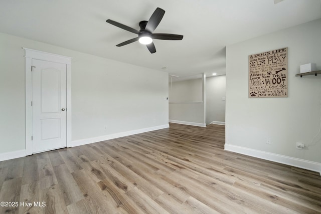 spare room with wood finished floors, a ceiling fan, and baseboards