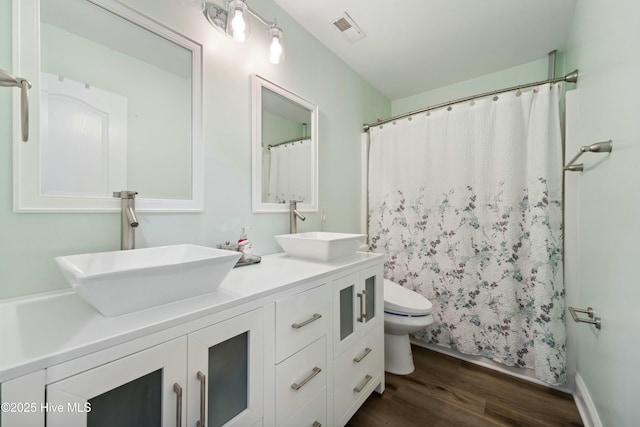 bathroom with a sink, visible vents, toilet, and wood finished floors