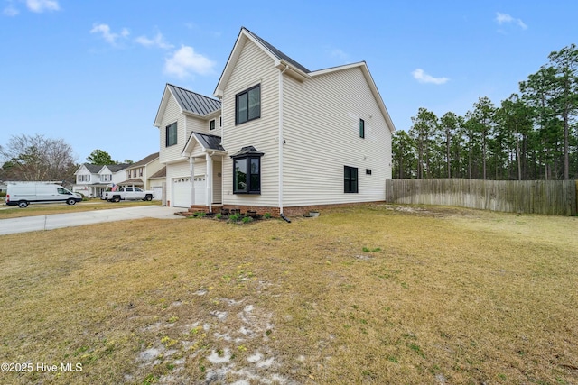 exterior space with fence, metal roof, a yard, driveway, and a standing seam roof