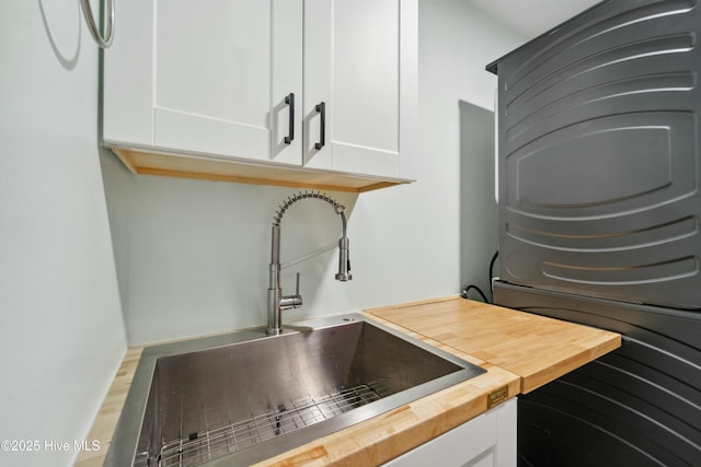 kitchen with white cabinets, wood counters, and a sink