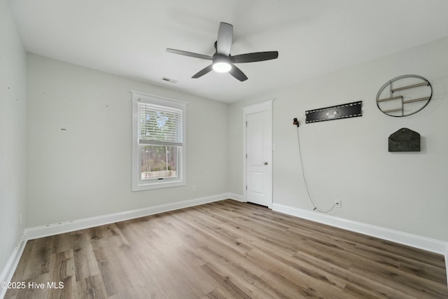 unfurnished bedroom featuring ceiling fan, visible vents, baseboards, and wood finished floors